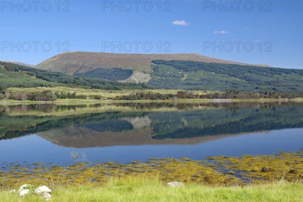 A loch with a clear reflection of mountains under a bright blue sky, Loch Eil, Scotland, Great Britain