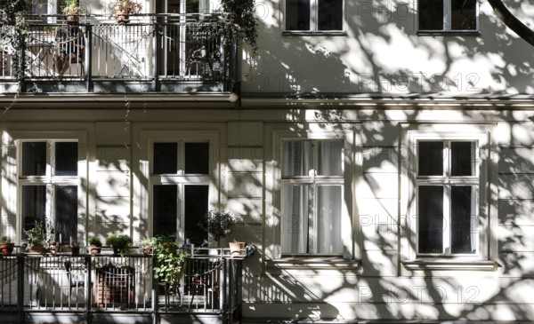 Facade of a multi-storey residential building with classical architecture with balconies with plants, shadows of leaves and branches on the house wall, Berlin, 24.09.2025, Berlin, Berlin, Germany