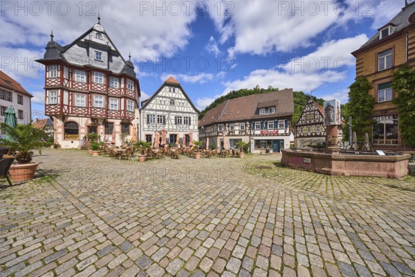 Old town, historic half-timbered houses, fountain, market fountain, cobblestone square, outdoor area of a restaurant, visitors as secondary motif, blue sky, cumulus clouds, market square, intersection between Großer Markt, Marktstraße, Amtsgasse, Mühlgasse and Schunkengasse, Heppenheim, Odenwald, Bergstraße district, Hesse, Germany
