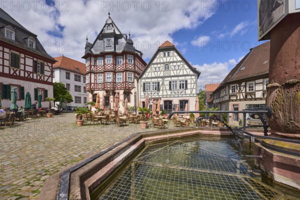Old town, stone fountain, water, historic half-timbered houses, cobblestone square, outdoor area of a restaurant, visitors as secondary motif, blue sky, cumulus clouds, market square, intersection Großer Markt, Marktstraße and Amtsgasse, Heppenheim, Odenwald, Bergstraße district, Hesse, Germany