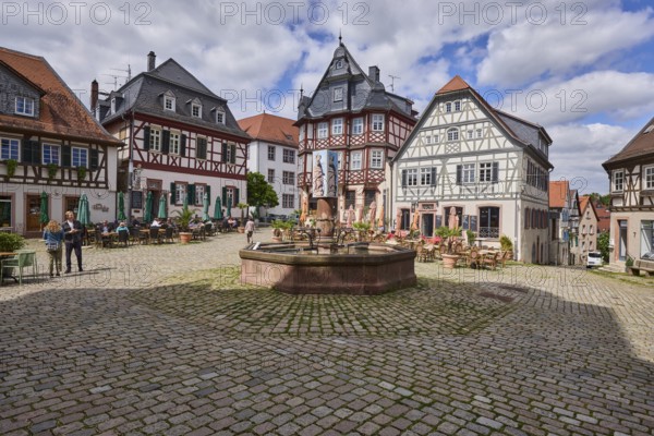 Old town, historic half-timbered houses, stone fountain, market fountain, cobblestone square, outdoor area of a restaurant, pedestrians as accessories, visitors as secondary motif, blue sky, cumulus clouds, market square, intersection Großer Markt, Marktstraße and Amtsgasse, Heppenheim, Odenwald, Bergstraße district, Hesse, Germany