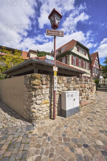 Old town, lantern, signpost to the museum, quarry stone wall, historic half-timbered houses, buildings, trees, blue sky, cumulus clouds, intersection Kleine Bach with Amtsgasse, Heppenheim, Odenwald, Bergstrasse district, Hesse, Germany