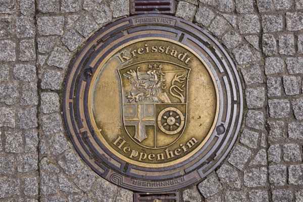 Manhole cover, district town of Heppenheim, golden, pavement made of paving stones, rain gutter, Heppenheim, Odenwald, Bergstrasse district, Hesse, Germany