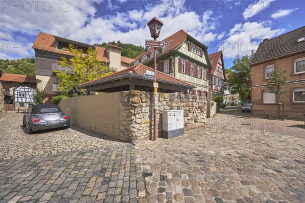 Old town, half-timbered houses, buildings, town gate Sickinger Tor, town fortifications, cobblestone pavement, lantern, signpost to the museum, quarry stone wall, car, trees, blue sky, cumulus clouds, intersection Kleine Bach with Amtsgasse, Heppenheim, Odenwald, Bergstraße district, Hesse, Germany