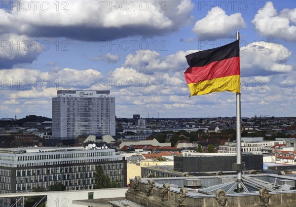 View from the Reichstag dome of a German flag in the wind with the Charité bed tower, Reichstag building, Berlin, Germany