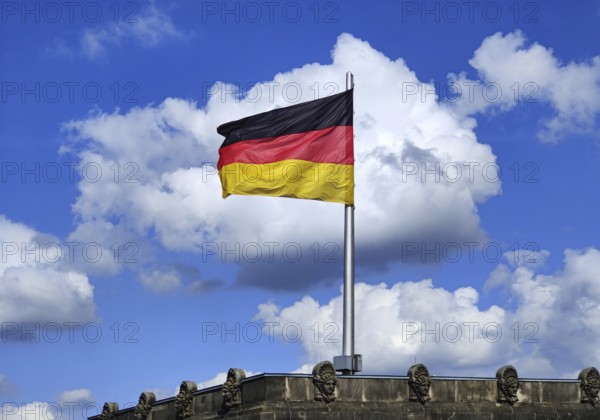 View from the Reichstag dome of a German flag in the wind in front of a cloud, Reichstag building, government district, Berlin, Germany