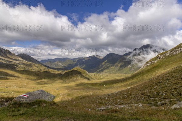 View from Passo del Sole in Alpe Carorescio with Piano Grande plateau and hiking trail marker, Quinto, Ticino, Switzerland