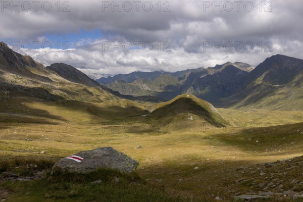 View from Passo del Sole in Alpe Carorescio with Piano Grande plateau and hiking trail marker, Quinto, Ticino, Switzerland