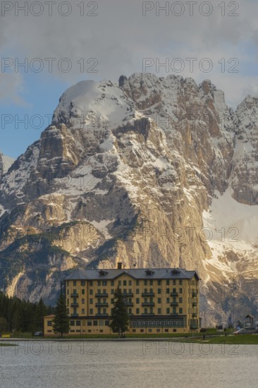 View over Lake Misurina to a building on the shore of the lake with a view towards the Sorapis mountain group, Misurina, Dolomites, Province of Belluno, Veneto, Italy
