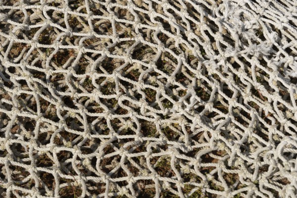 Fishing net lying on the ground, textured background