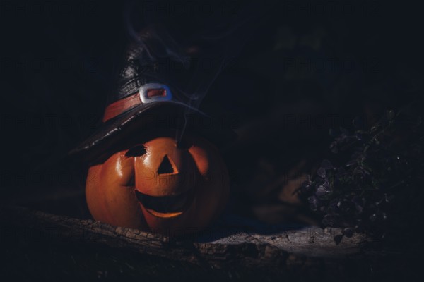 Pumpkin lantern with witch's hat in a spooky, dark setting