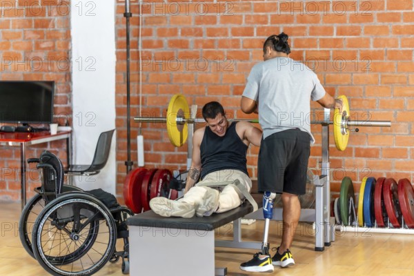 Man with prosthetic leg spotting another man with leg injuries or absence, who struggles with a barbell on a bench press, demonstrating dedication to overcoming challenges in a fitness setting