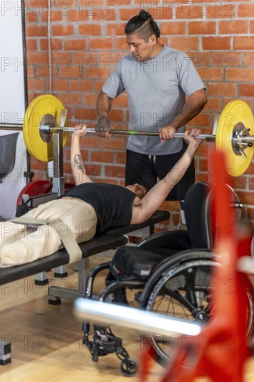 Adaptive athlete in a wheelchair performing bench press exercises with a spotter at the gym, demonstrating physical strength, determination, and inclusive fitness training