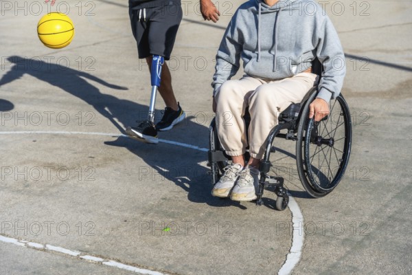 Two people with different physical disabilities staying active on an outdoor basketball court, one using a wheelchair and the other wearing a prosthetic leg while dribbling a ball