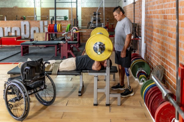 Two determined men training in a gymone bench pressing weights while his teammate with a prosthetic leg stands supportivelyshowing adaptive strength and inclusion in sport