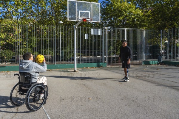 Two young men with disabilities, one using a wheelchair and the other a prosthetic leg, enjoying a game of basketball together on an urban court, promoting inclusion and adaptive sports