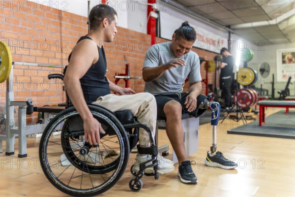 Two young men with disabilities one in a wheelchair, one with a prosthetic leg laughing and bonding while training together in a gym, showing inclusion and strength