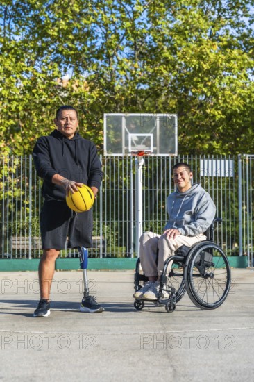 Two men, one with a prosthetic leg holding a basketball and another sitting in a wheelchair, standing together on an outdoor basketball court demonstrating inclusivity in sports