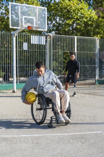 Young men with physical disabilities engaging in adaptive basketball. One person using a wheelchair and another with a prosthetic leg. Demonstrating inclusion and overcoming challenges through sports