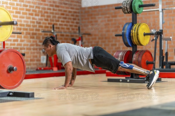 Athlete with a prosthetic leg doing push ups on a gym floor, showing determination, adaptive fitness and strength during rehabilitation and focused training session