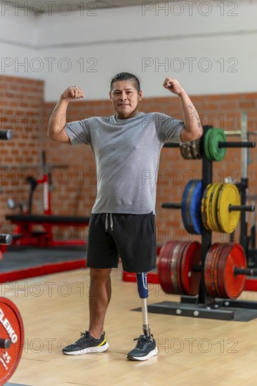 Amputee man with a prosthetic leg standing confidently in a gym, flexing his biceps and looking at camera, symbolizing strength, resilience and recovery through fitness rehabilitation