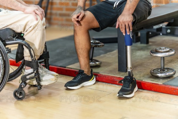 Disabled men, one in a wheelchair and another with a prosthetic leg, sharing a moment of camaraderie and connection after an adaptive workout session in a gym