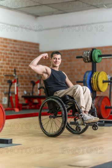 Young man in a wheelchair posing with a flexed bicep, showing determination and strength while training in an adaptive fitness gym for disabled athletes