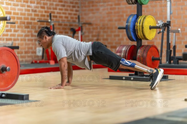 Athlete with prosthetic leg doing push ups on a gym floor, showcasing adaptive strength training, determination and focused bodyweight workout for rehabilitation and fitness development