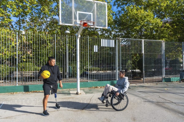 Disabled men, one using a wheelchair and the other wearing a prosthetic leg, playing basketball on an outdoor court, symbolizing inclusion and adaptive sport