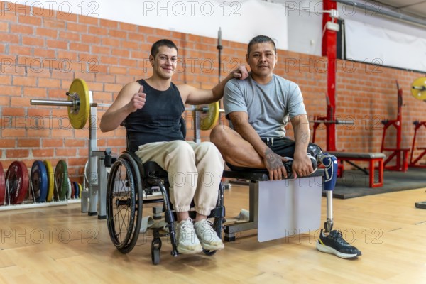 Two adaptive athletes standing together in a gym, one man uses a wheelchair and the other has a prosthetic leg, both embracing fitness and camaraderie