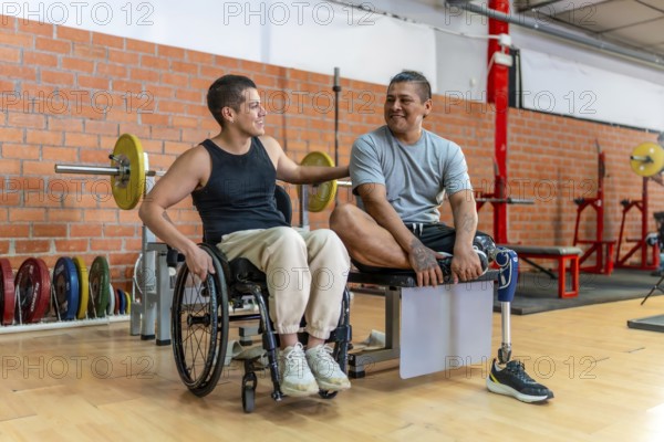 Two adaptive athletes, one in a wheelchair and one with a prosthetic leg, smiling and supporting each other while sitting in a gym, showing inclusion, determination and wellness