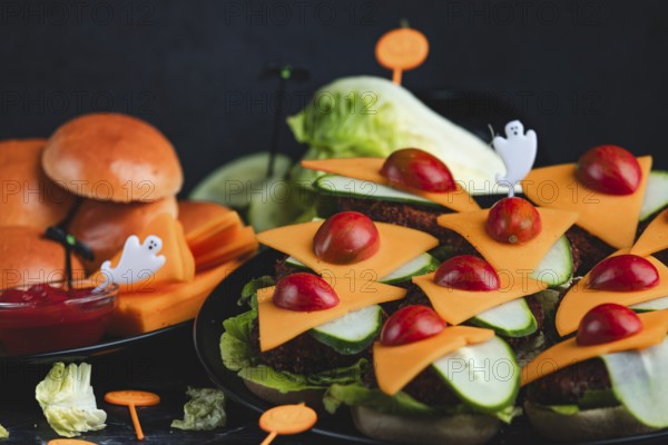 Burger buns with cheese, tomatoes, salad and Halloween decorations