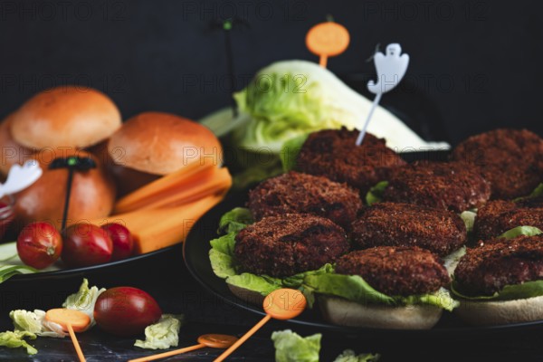 Burger buns with patties, salad, ingredients and Halloween decoration