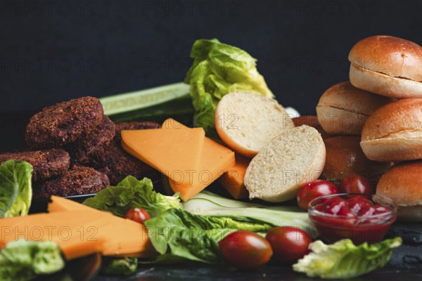 Meatballs and cheese on a bed of lettuce with burger buns and fresh vegetables