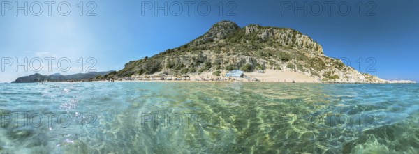 Picturesque Tsambika beach with clear water and rocky mountain landscape under a blue sky, Tsambika beach, Archaggelos, Rhodes island, Greece