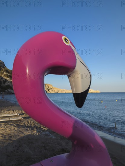 Pink flamingo pedal boat on Tsambika sandy beach with sea in the background at sunset, Tsambika beach, Archaggelos, Rhodes island, Greece
