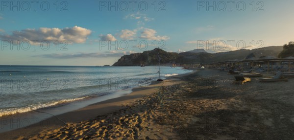 Sunset at Tsambika beach with calm sea, mountains in the background and a peaceful sky, Tsambika beach, Archaggelos, Rhodes island, Greece