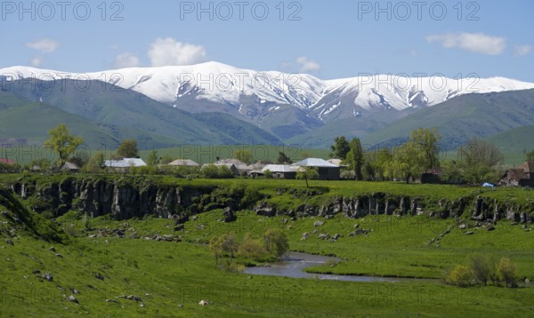 A village in a green landscape with snow-capped mountains in the background, Saratovka, Lesser Caucasus, Lorikeet Province, Armenia