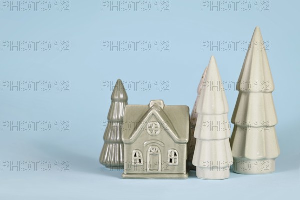 Light green ceramic Christmas trees and house on blue background