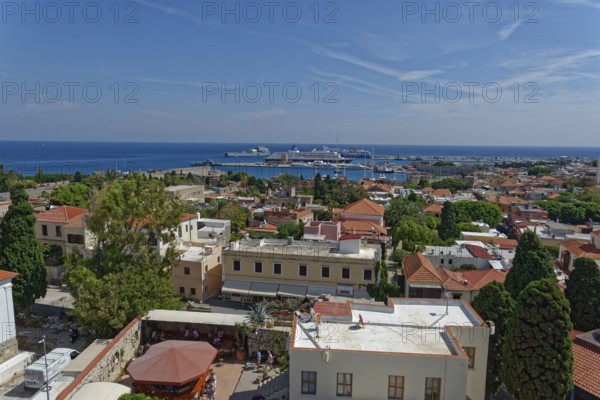 Overview of a town on the coast with harbour, many buildings and trees, Roloi Clock Tower, Medieval Town of Rhodes, Rhodes Island, Greece