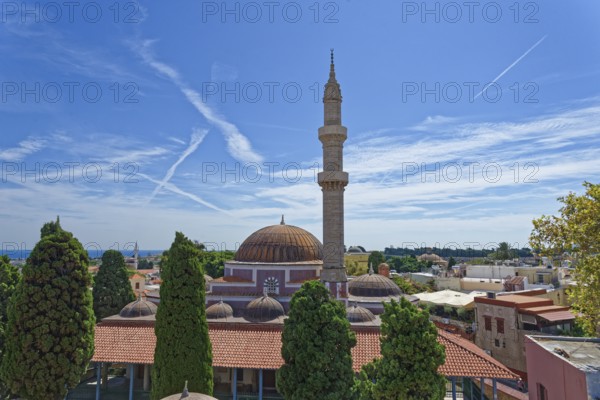 A minaret and domes in a tranquil cityscape with cypress trees and blue sky, Suleiman Mosque, Medieval Town of Rhodes, Rhodes Island, Greece
