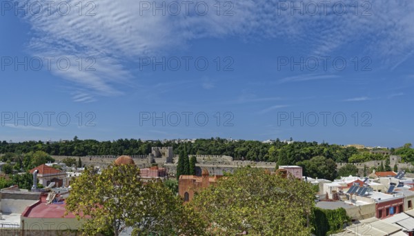 View of a historic old town with many trees and traditional buildings under a clear blue sky, Medieval Town of Rhodes, Rhodes Island, Greece