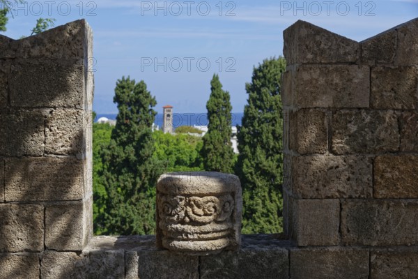 View from a stone wall with battlements of green trees and the distant sea under a blue sky, Grand Master's Palace, Medieval Town of Rhodes, Rhodes Island, Greece