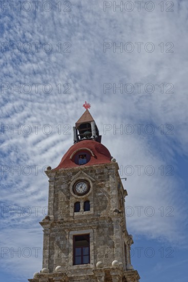 An ancient bell tower with red roof and clock in front of a blue sky with clouds, Roloi Clock Tower, Medieval Town of Rhodes, Rhodes Island, Greece