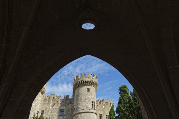 View through a stone arch to a medieval castle with tower under a blue sky, Grand Master's Palace, Medieval Town of Rhodes, Rhodes Island, Greece