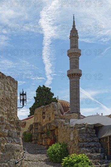 A minaret with a blue sky and ancient walls in a tranquil, historic setting, Suleiman Mosque, Medieval Town of Rhodes, Rhodes Island, Greece