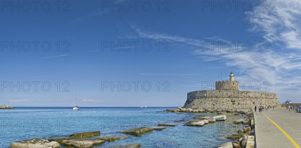 Fort of Saint Nikolaos stretches along the coast in the bright sunshine, Mandraki harbour, Medieval Town of Rhodes, Rhodes Island, Greece