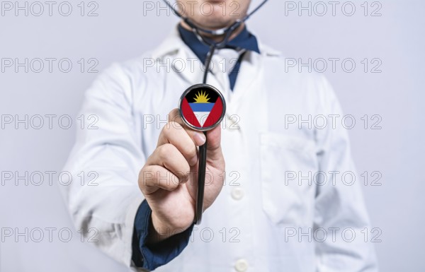 Doctor hands holding stethoscope with Antigua and Barbuda flag. Antigua and Barbuda health and care concept