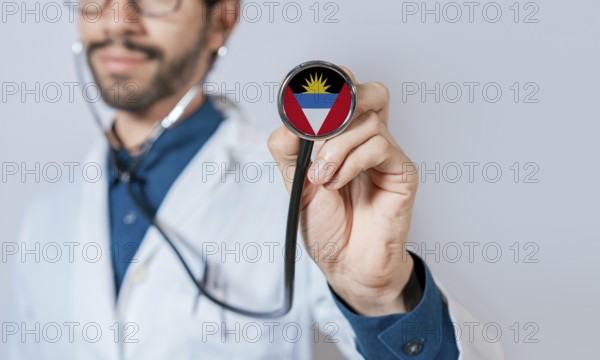 Doctor holding stethoscope with Antigua and Barbuda flag. Antigua and Barbuda health and care concept, Antigua and Barbuda flag on stethoscope
