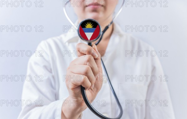 Female doctor holding stethoscope with Antigua and Barbuda flag. National health system of Antigua and Barbuda